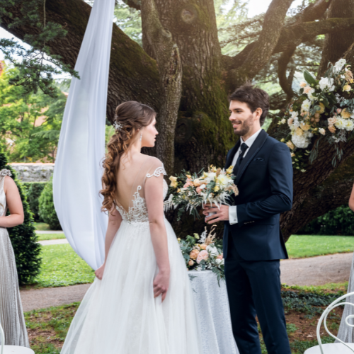 Un couple heureux en tenue de mariage, assis dans un décor d'intérieur chaleureux.