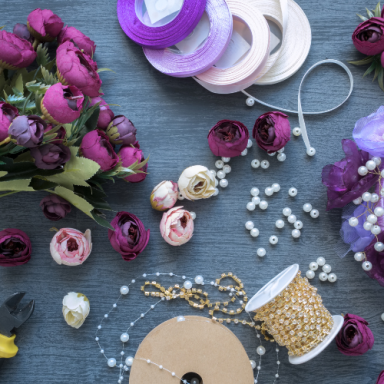 Fleurs colorées, rubans, perles et fournitures de bricolage sur une surface grise.