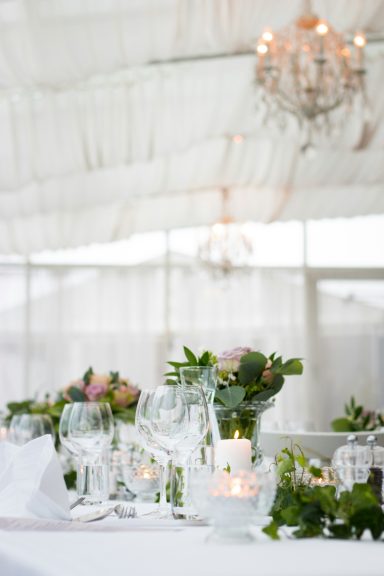 Table élégamment dressée avec des fleurs et des bougies, sous un lustre.