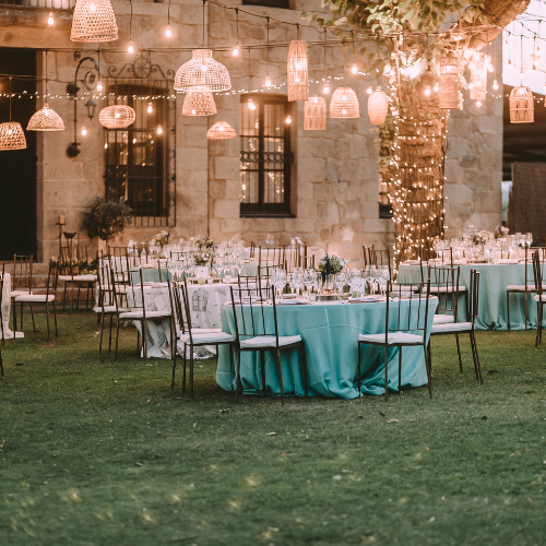 Décor de réception en plein air avec tables turquoise et lanternes suspendues.
