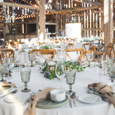 Table élégamment dressée avec vaisselle et décorations dans une grange lumineuse.