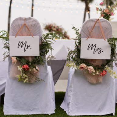 Chaises décorées avec des étiquettes "Mr." et "Mrs." ornées de fleurs.