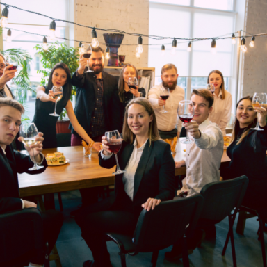 Groupe de personnes en costume levant des verres lors d'une célébration autour d'une table.