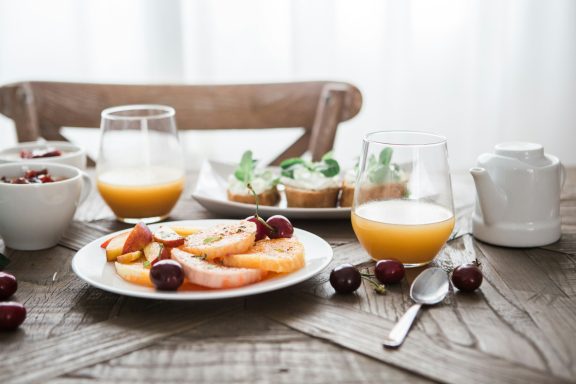 Petit-déjeuner avec des fruits, jus d'orange et plats sur une table en bois.