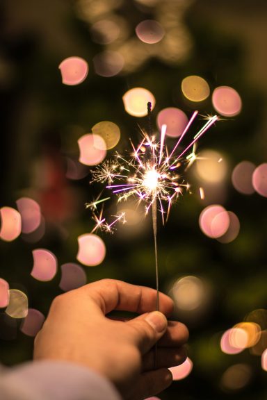 Main tenant une étincelle allumée, avec un fond flou de lumières de Noël.