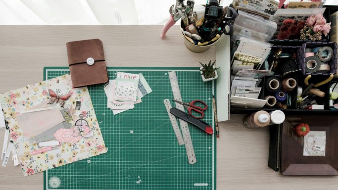 Espace de travail créatif avec outils de scrapbooking et fournitures variées.