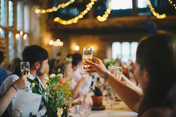 Repas festif avec des convives levant leurs verres au champagne dans une salle décorée.